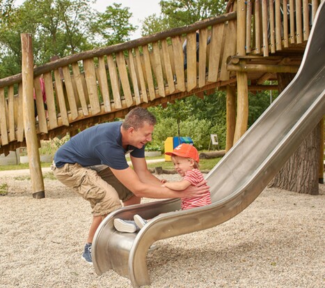 A man catching a child at the end of the slide at the adventure and nature playground