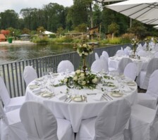 Tables festively laid in white with white roses on the terrace of the restaurant GAUMENWEIDE by the water lily pond